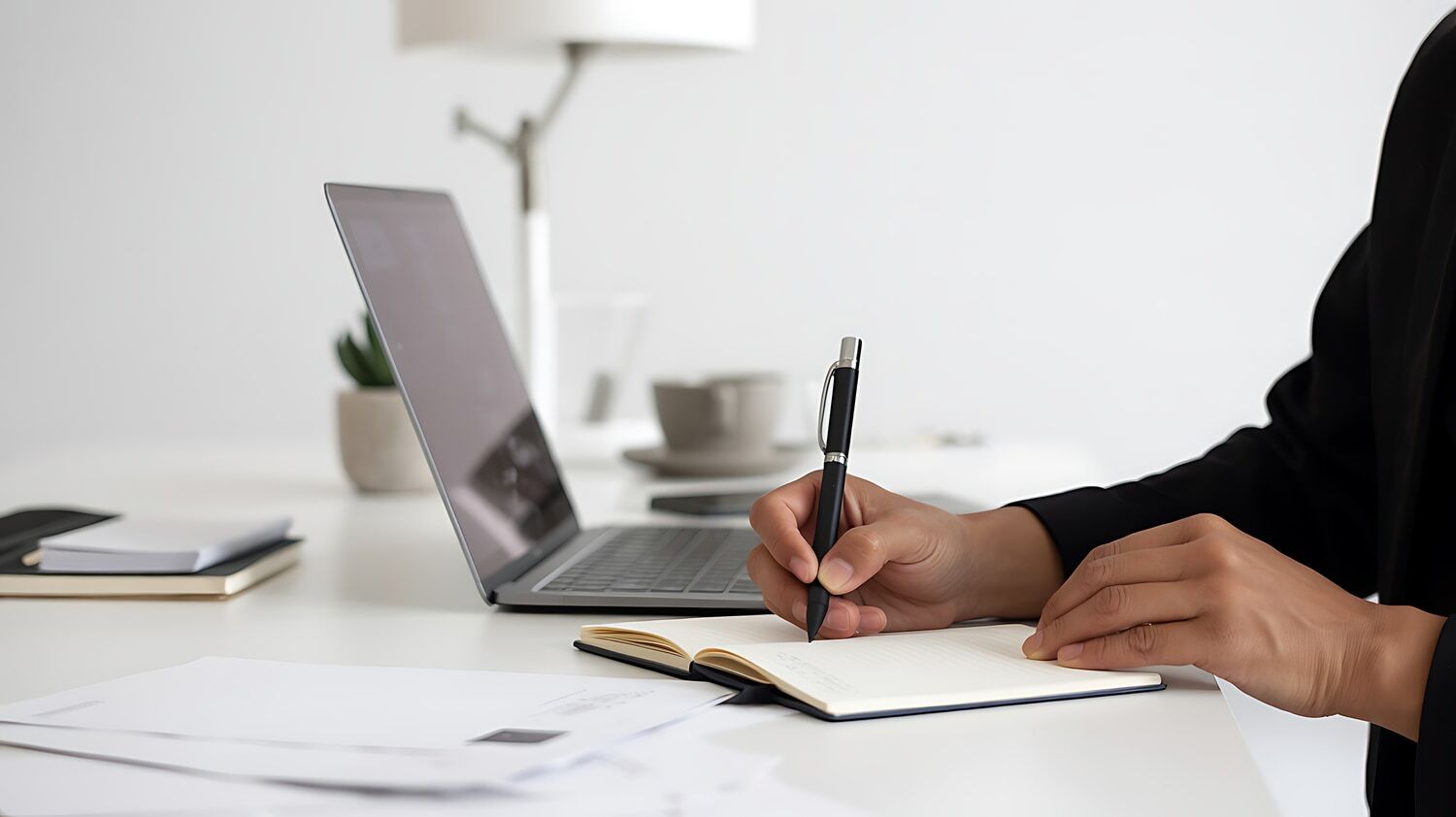 Writing notes beside a laptop